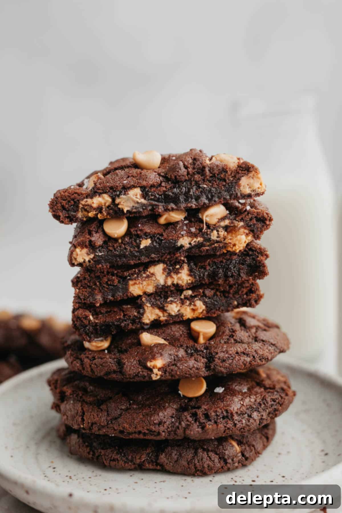 Decadent Caramel Chocolate Cookies 8 A stack of perfectly baked chocolate caramel cookies, with one cookie expertly cut in half to reveal its fudgy interior and melted caramel pockets.