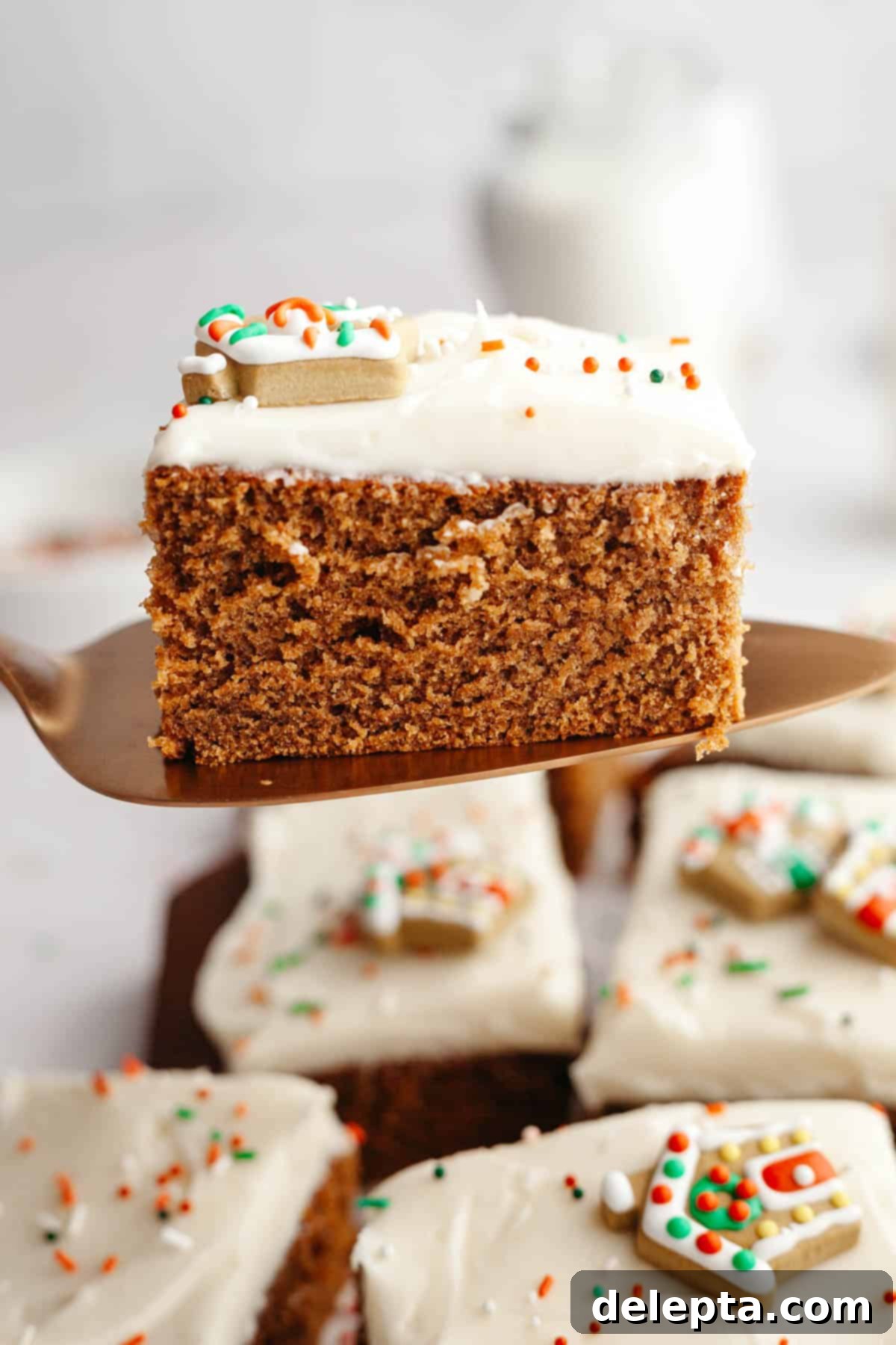 Cozy Gingerbread Cake with Cream Cheese Frosting 11 A cake server lifting up a slice of gingerbread cake with cream cheese frosting.