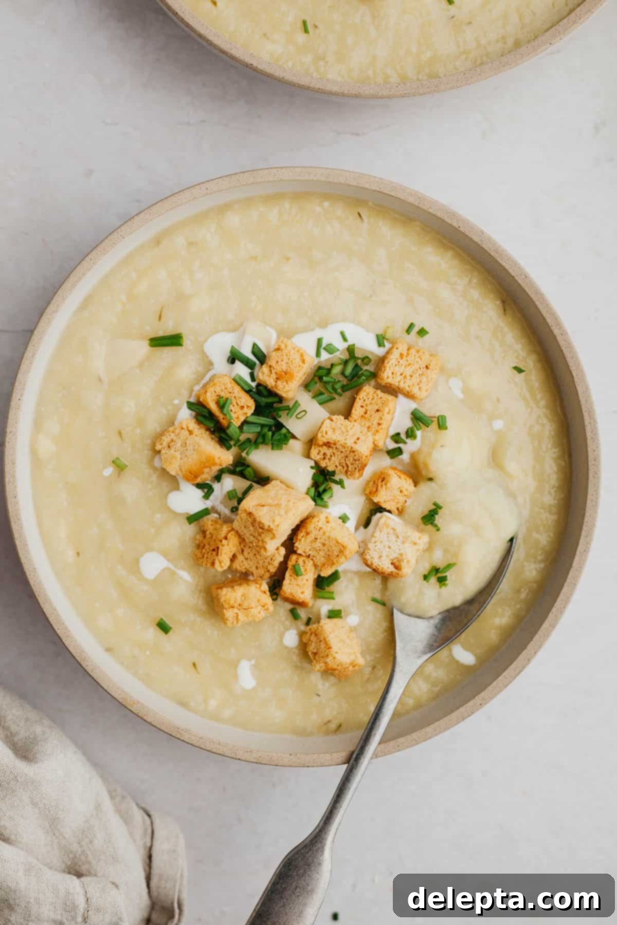 Creamy 30-Minute Leek Potato Cauliflower Soup 2 A steaming bowl of creamy leek, potato, and cauliflower soup, garnished with golden croutons and fresh chopped dill.