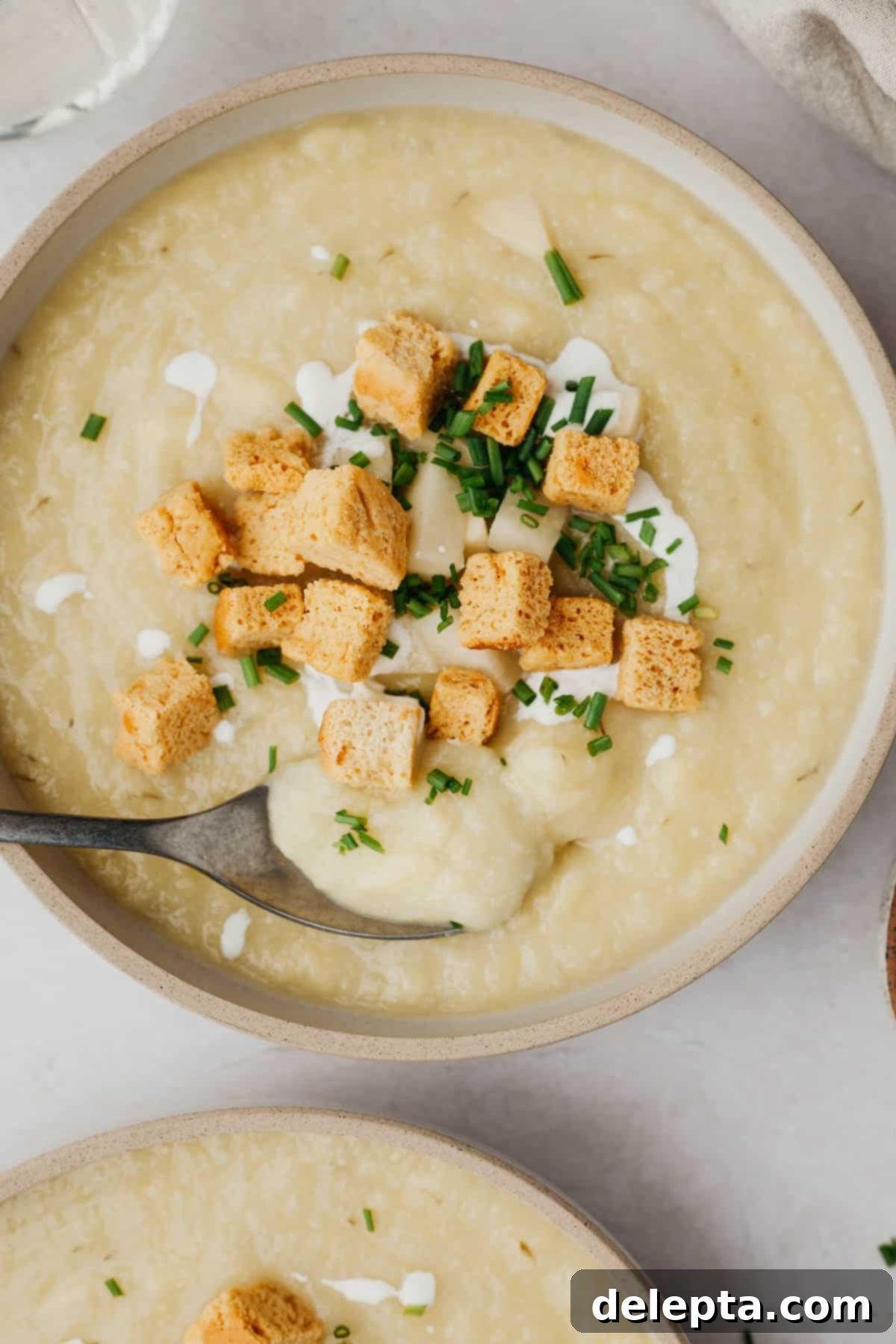 Creamy 30-Minute Leek Potato Cauliflower Soup 6 A vibrant bowl of creamy cauliflower, leek, and potato soup, beautifully topped with golden croutons and fresh chopped dill.