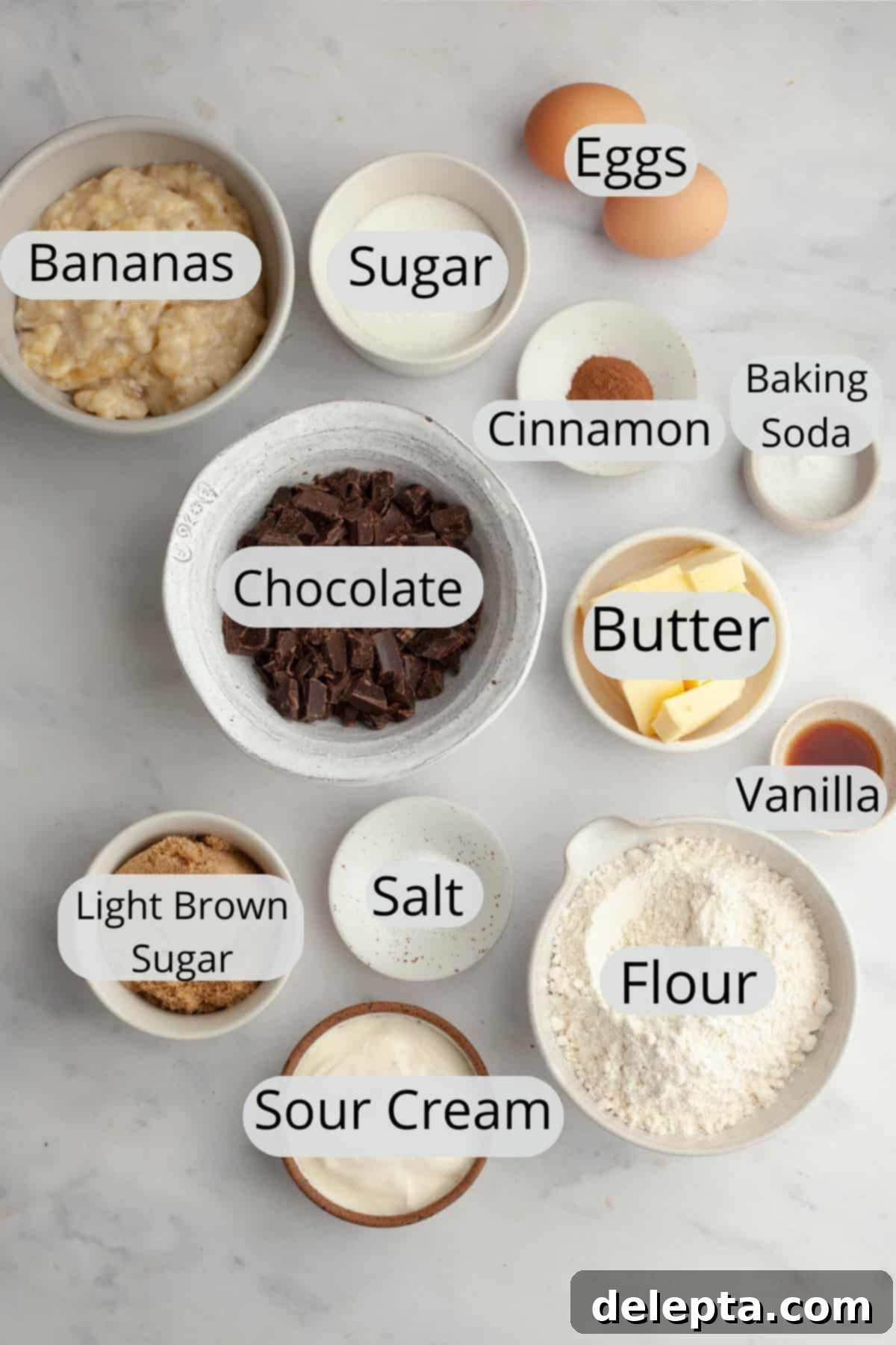 Seriously Moist Chocolate Chunk Banana Bread 4 All the necessary ingredients for making chocolate chunk banana bread, neatly portioned into small bowls on a countertop.