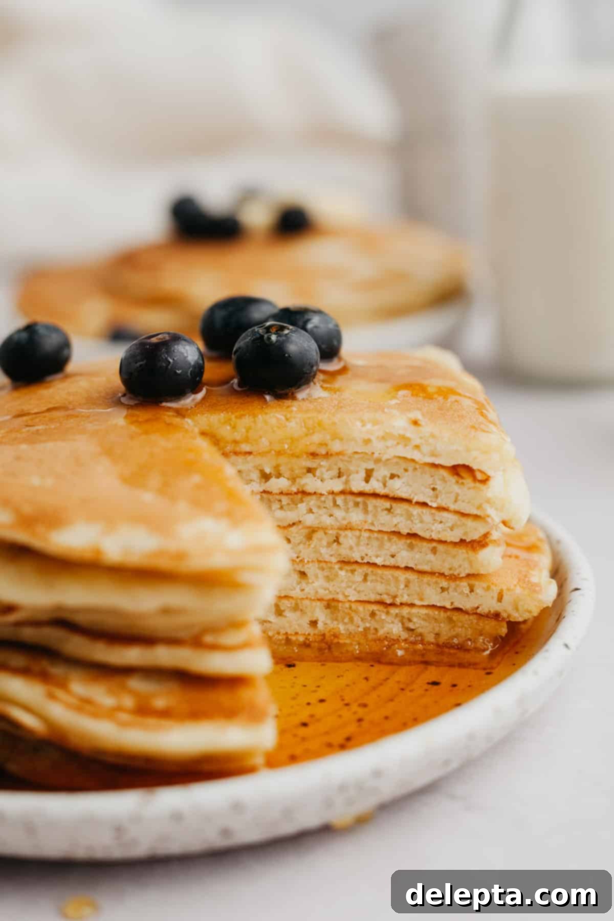 Decadent Sweet Cream Pancakes 2 A stack of golden brown, fluffy sweet cream pancakes topped with fresh blueberries and a generous drizzle of golden maple syrup, ready to be enjoyed.