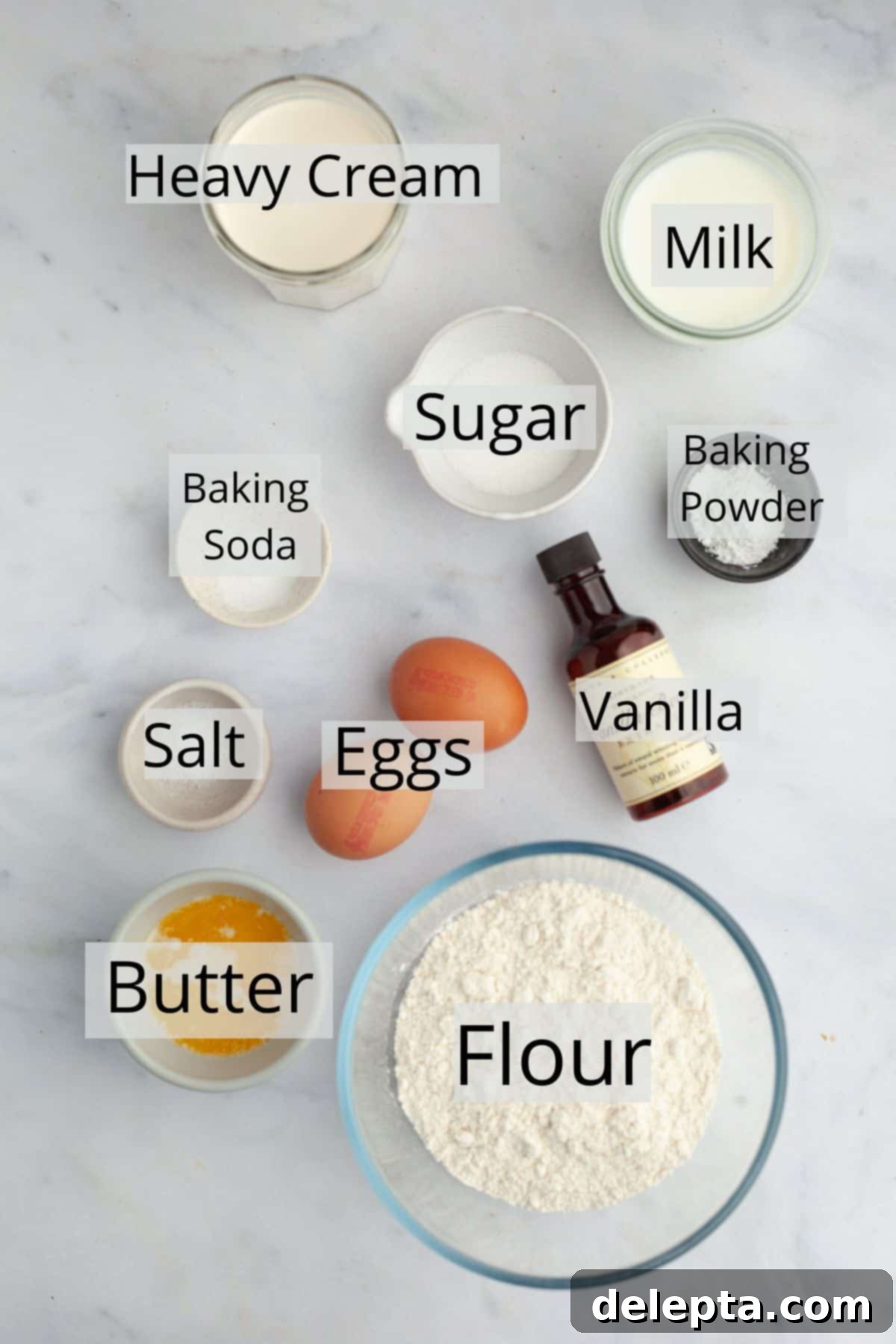 Decadent Sweet Cream Pancakes 3 All the essential ingredients neatly arranged in small white bowls, including flour, heavy cream, milk, eggs, sugar, salt, baking powder, baking soda, vanilla extract, and melted butter, ready to be combined for sweet cream pancakes.