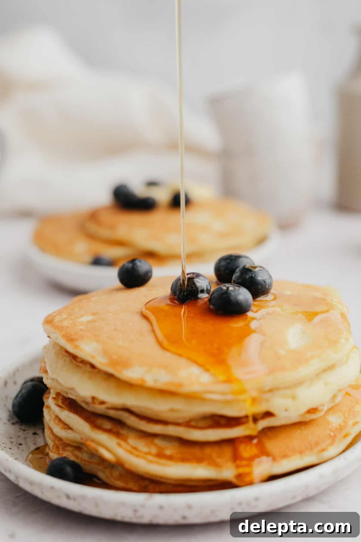 Decadent Sweet Cream Pancakes 6 A glorious stack of perfectly cooked sweet cream pancakes, generously topped with an abundance of fresh blueberries, with a stream of golden maple syrup cascading down the sides.