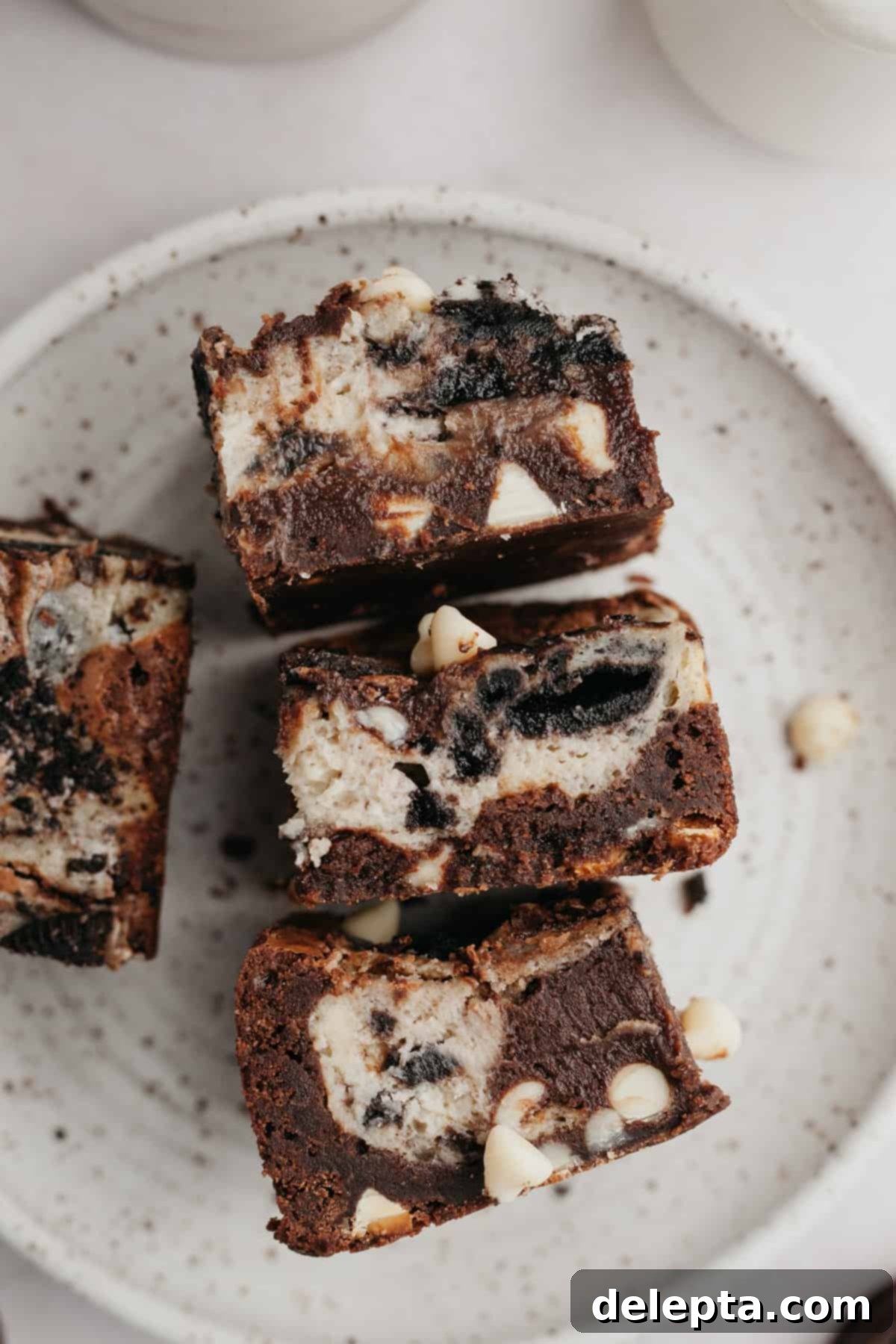 Oreo Cheesecake Swirl Brownies 8 Three Oreo cream cheese brownies arranged on a small plate for serving, showcasing their delicious layers.