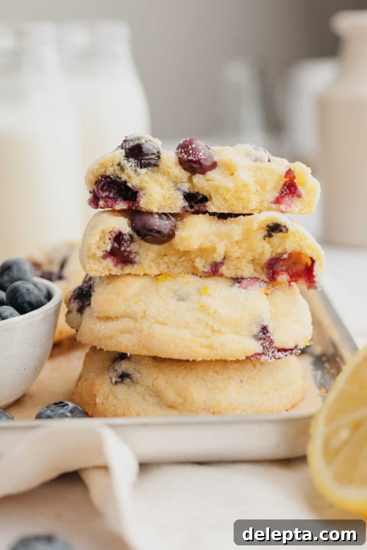 Pillowy Lemon Blueberry Delights 2 A stack of lemon blueberry cookies cut in half, showcasing the soft interior and fresh blueberries.