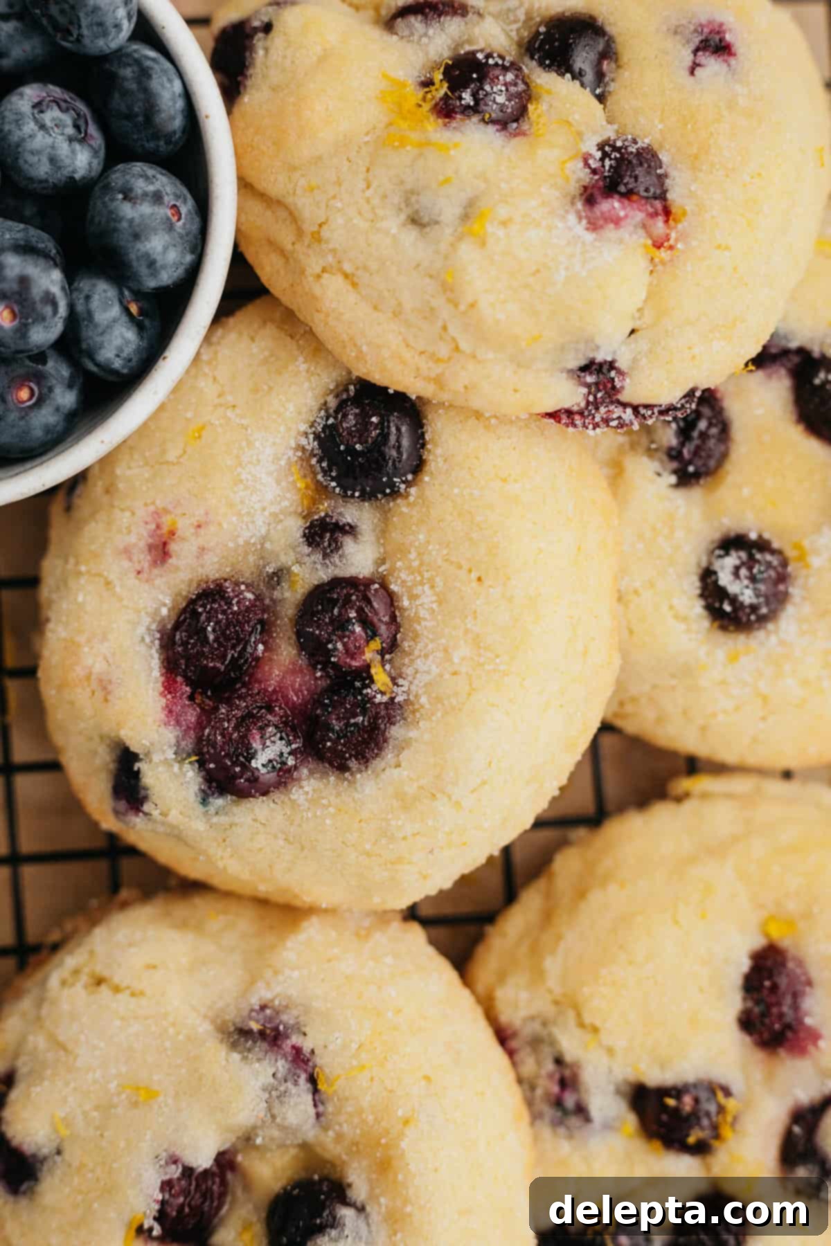 Pillowy Lemon Blueberry Delights 7 Several blueberry lemon cookies cooling on a wire rack after being freshly baked.