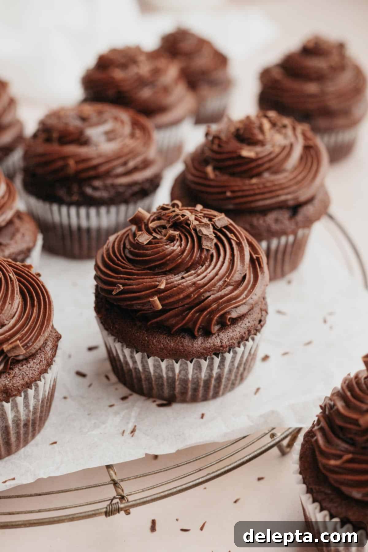 Decadent Chocolate Fudge Cupcakes 9 Chocolate cupcakes with chocolate frosting on parchment paper.