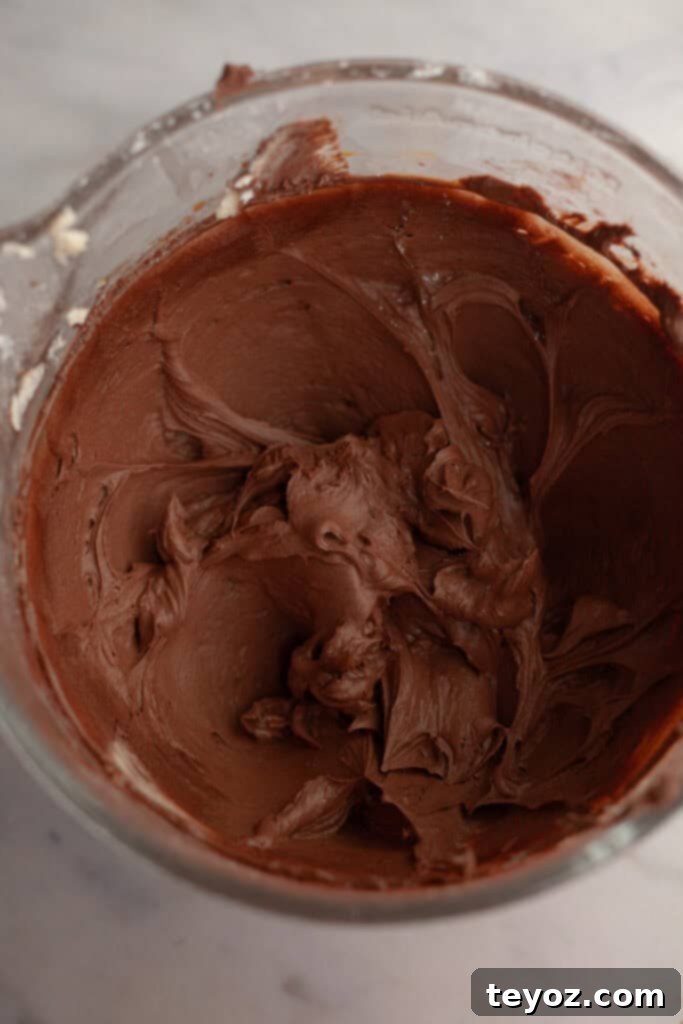 A pristine glass bowl filled with rich, smooth mocha frosting, its velvety texture and deep color making it look irresistible and ready to be applied to the cake.