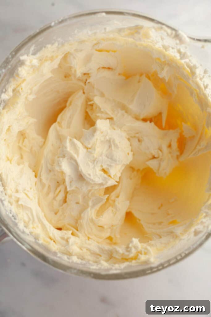 A glistening glass bowl filled with smooth, pristine white buttercream frosting, perfectly prepared and ready for flavoring and coloring.