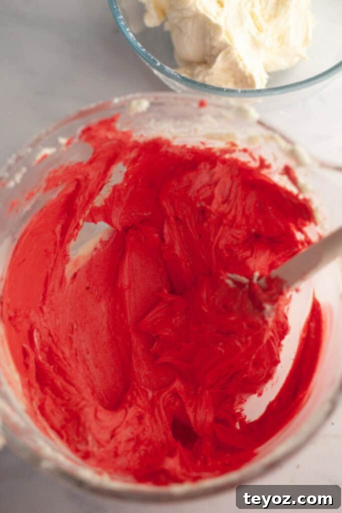 A glass bowl showcasing vibrant, rich red frosting, meticulously achieved using a high-quality food gel, destined for the striking candy cane filling.