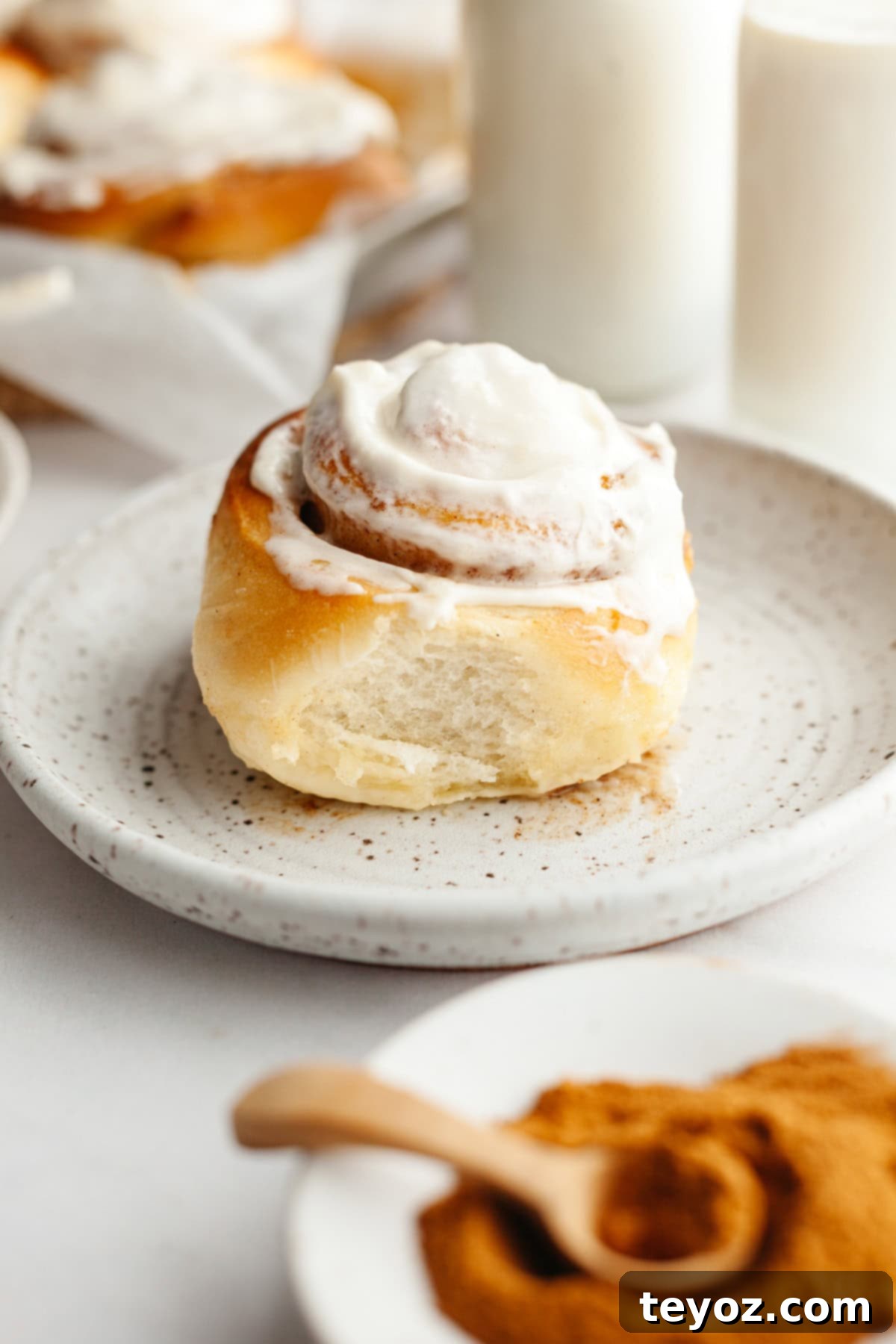 A single cinnamon roll with cream cheese icing on a small plate, ready to be enjoyed.