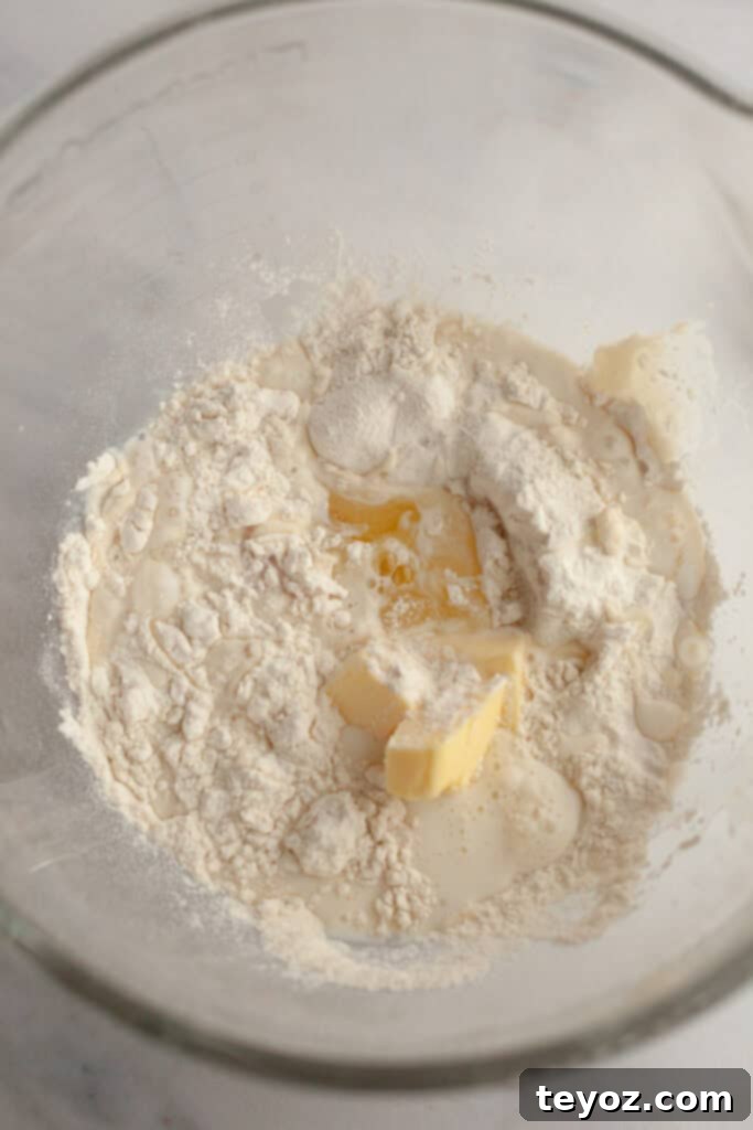 A glass bowl with flour, butter, milk, and yeast, ready to be combined with the tangzhong.