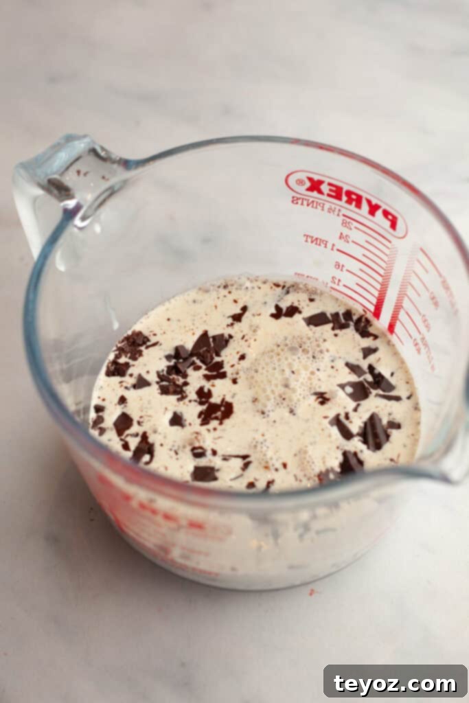 Aşağıdaki başlığı İngilizce'ye çevir ve özgünleştir: Black Forest Yule Log (Bûche de Nöel) Dark Chocolate Cherry Yule Log 11 A glass jug with chopped chocolate and cream, the beginnings of a rich chocolate ganache.