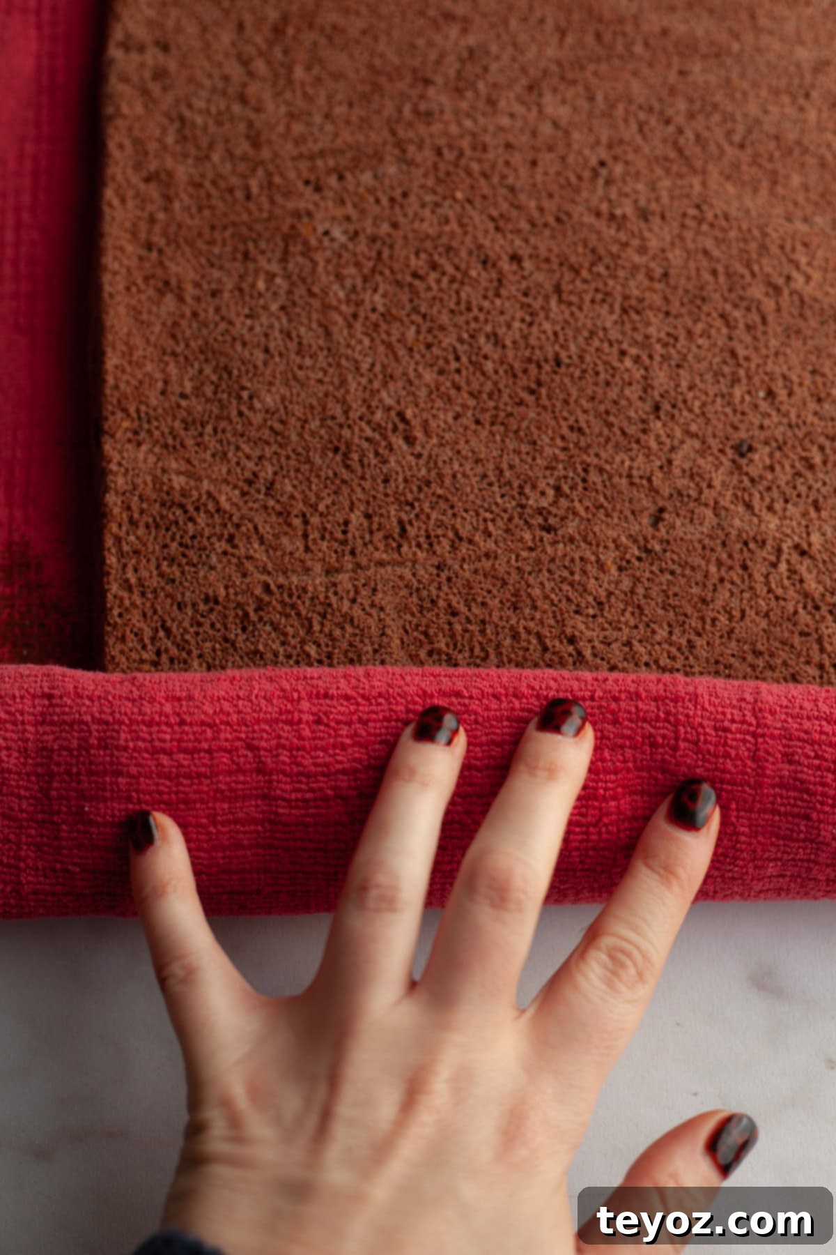 Aşağıdaki başlığı İngilizce'ye çevir ve özgünleştir: Black Forest Yule Log (Bûche de Nöel) Dark Chocolate Cherry Yule Log 8 Rolling up a chocolate cake in a red kitchen towel, demonstrating the technique for creating a perfect Yule log.