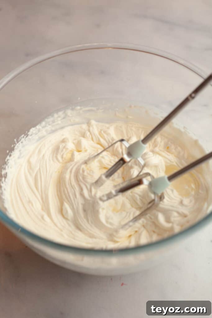 Aşağıdaki başlığı İngilizce'ye çevir ve özgünleştir: Black Forest Yule Log (Bûche de Nöel) Dark Chocolate Cherry Yule Log 9 A glass bowl with whipped cream, light and airy, ready to be spread onto the chocolate cake.