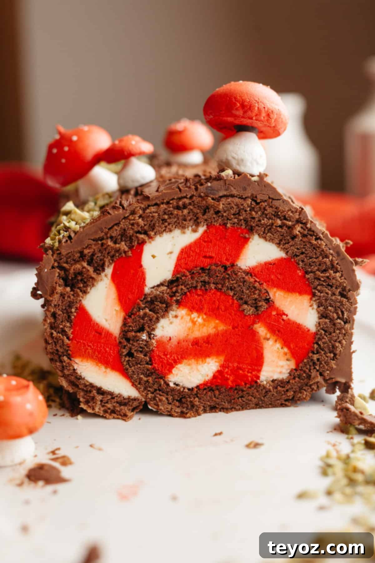 Chocolate Peppermint Dream Yule Log 2 A decadent chocolate yule log featuring a white and red striped filling, artistically decorated with meringue mushrooms on a pristine white platter.