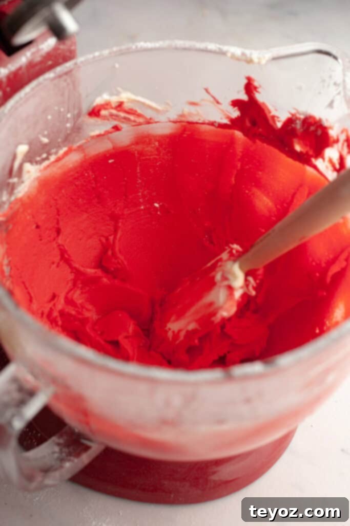 Chocolate Peppermint Dream Yule Log 11 A stand mixer bowl filled with vibrant red frosting, ready to be piped into candy cane stripes.