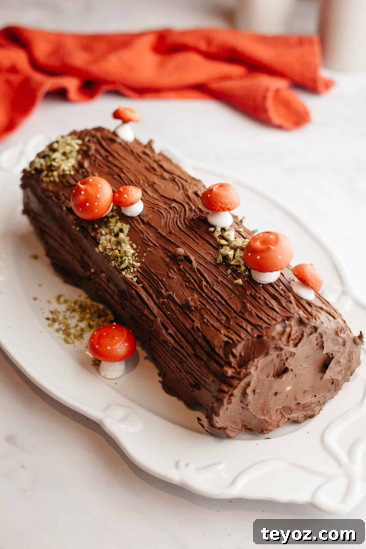 Chocolate Peppermint Dream Yule Log 14 A stunning chocolate yule log adorned with meringue mushrooms, sitting elegantly on a white platter.