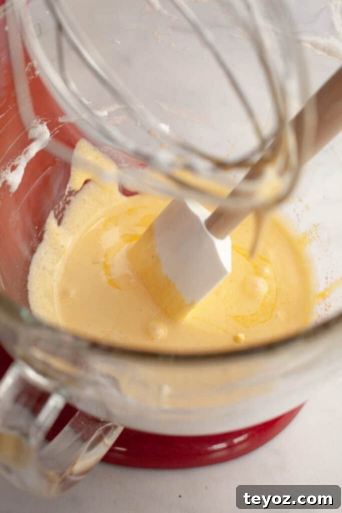 Chocolate Peppermint Dream Yule Log 5 A red stand mixer with a glass bowl, now containing a pale yellow mixture, representing the combined egg yolks and sugar.