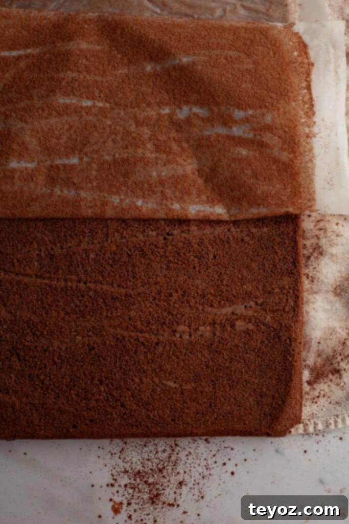 Chocolate Peppermint Dream Yule Log 8 A rectangular chocolate cake with parchment paper delicately being peeled off.