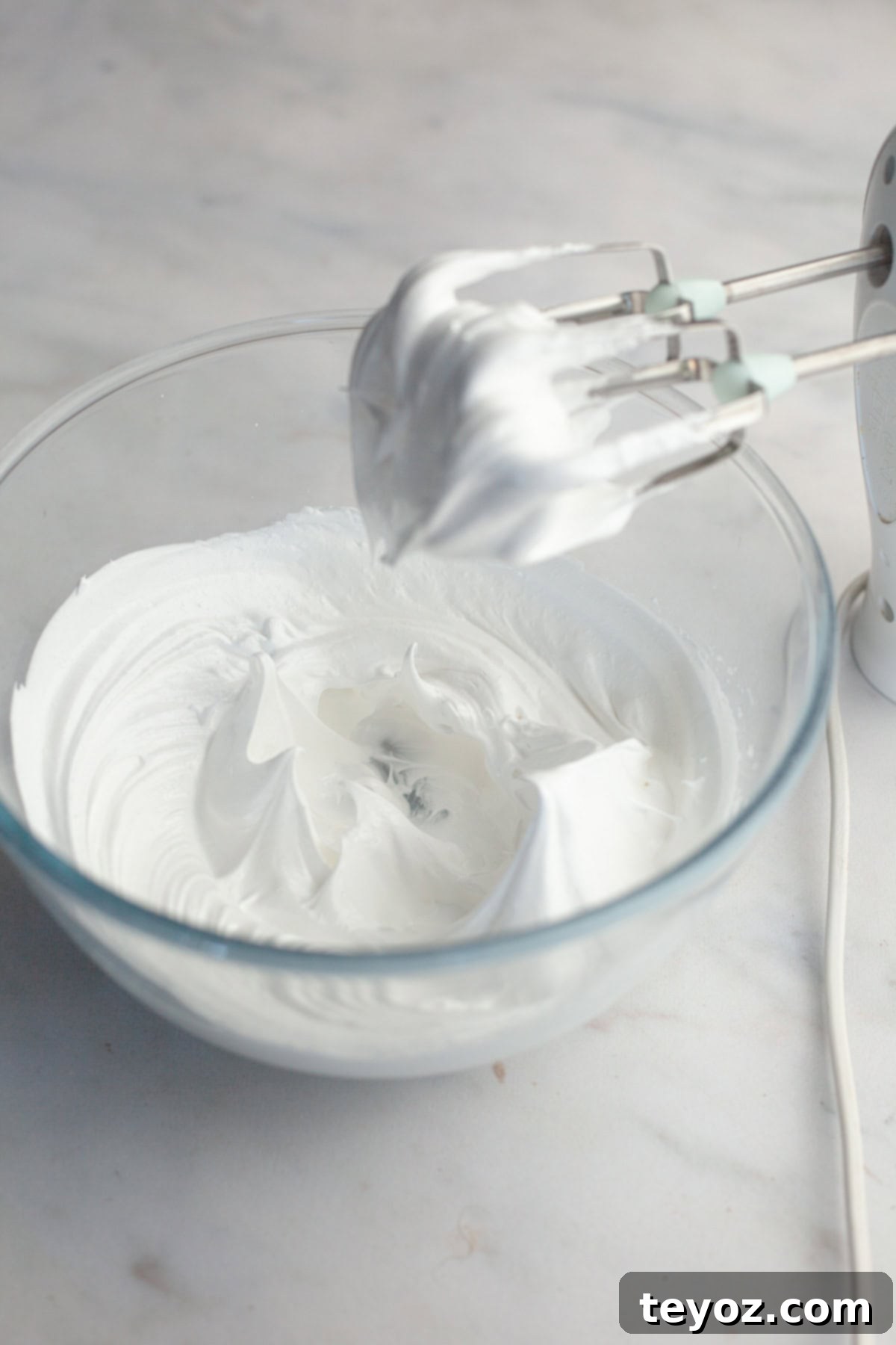 A glass bowl with stiff glossy meringue peaks.