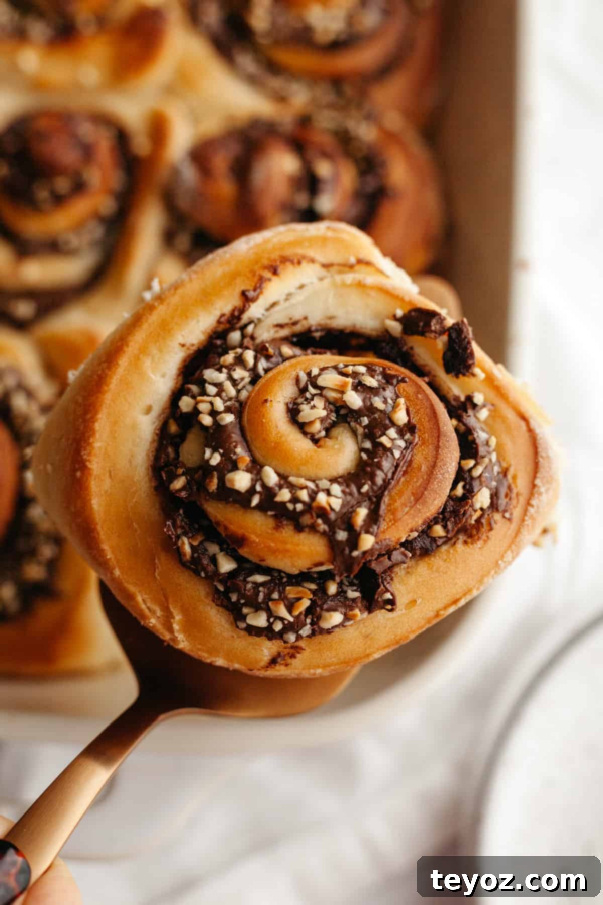 A close-up shot of a delectable Nutella cinnamon roll adorned with chopped hazelnuts, showcasing its soft texture and tempting filling.