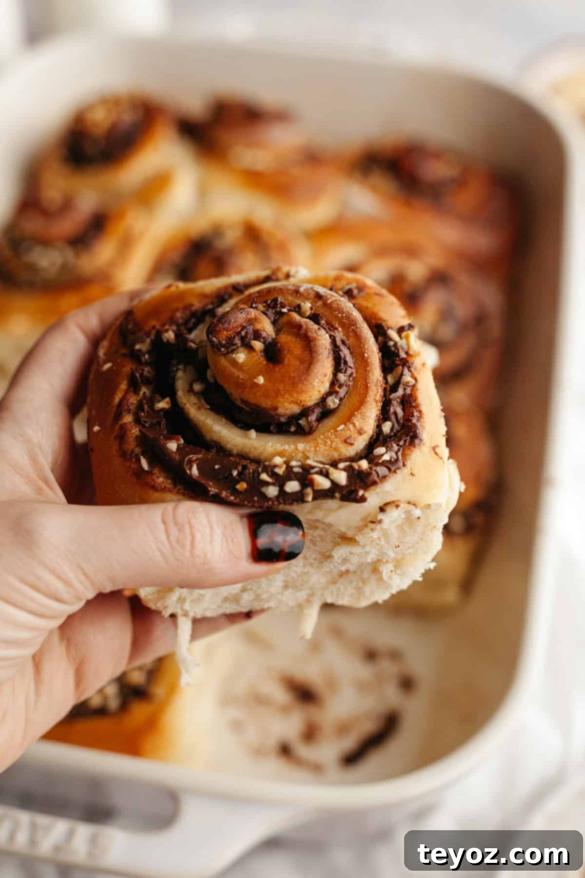 Another close-up of a perfectly baked Nutella cinnamon roll, showcasing its irresistible swirls of Nutella and crunchy hazelnut topping.