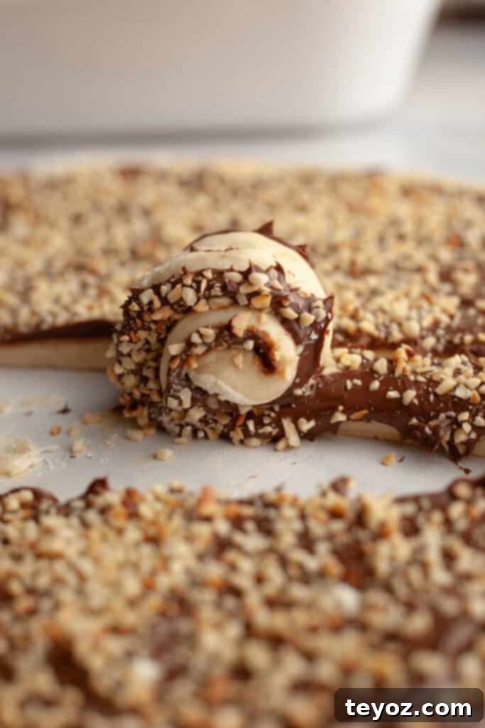 Demonstrating the process of rolling up the Nutella-covered dough into individual cinnamon rolls, creating those iconic swirls.
