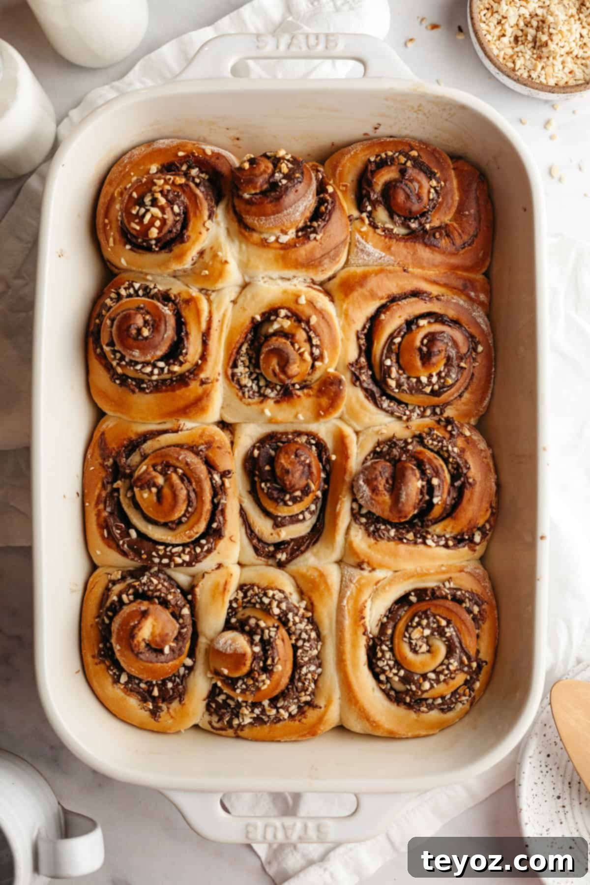 A large rectangular baking dish filled with freshly baked Nutella cinnamon rolls, showcasing their golden-brown crust and tempting aroma.