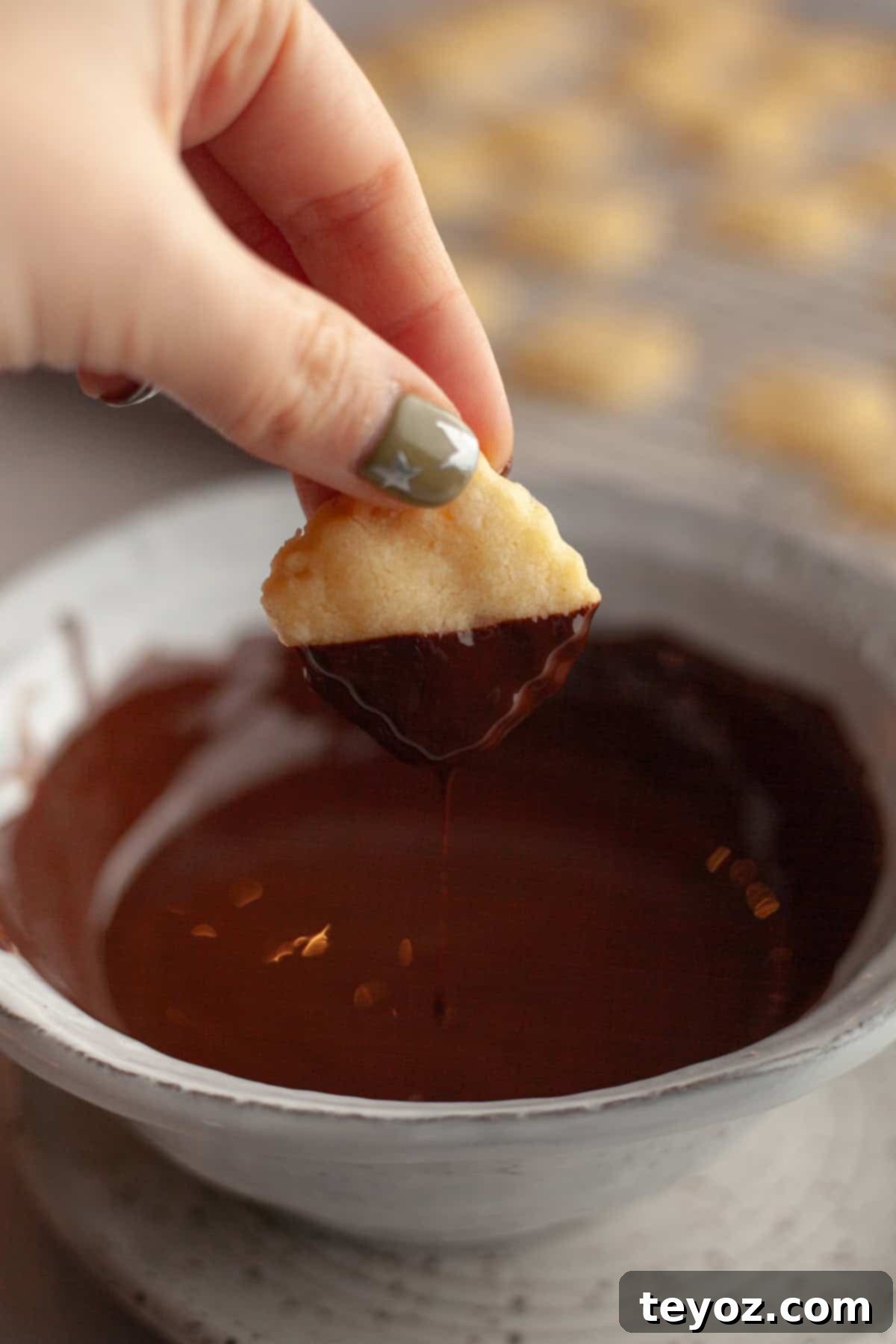 Double the Zing: Ginger Snap Delights 9 A hand carefully dipping a shortbread cookie into melted chocolate.