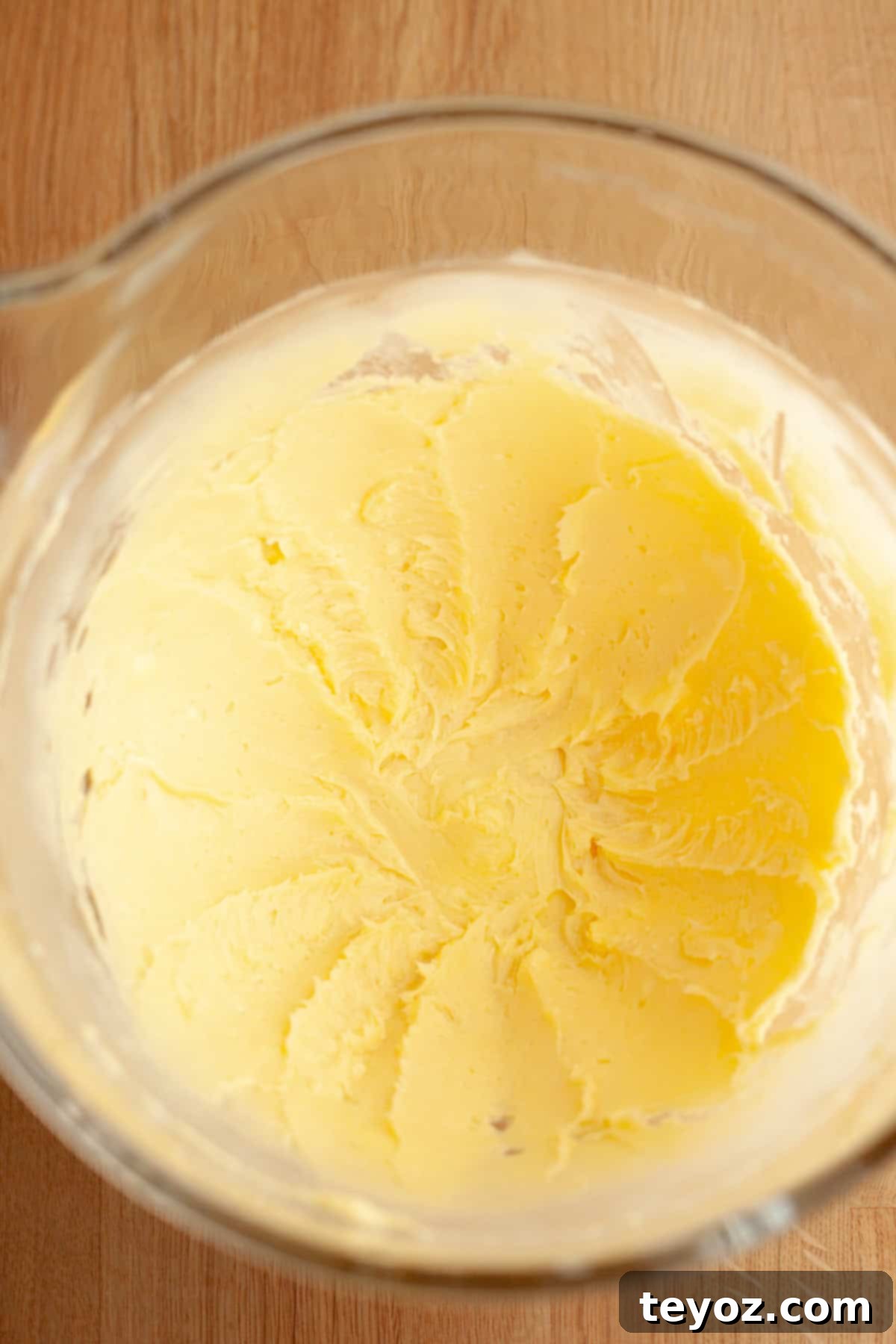 A captivating image showcasing the initial step of cinnamon shortbread cookie preparation, a pristine glass bowl filled with perfectly creamed butter and sugar, radiating a promise of delectable treats.