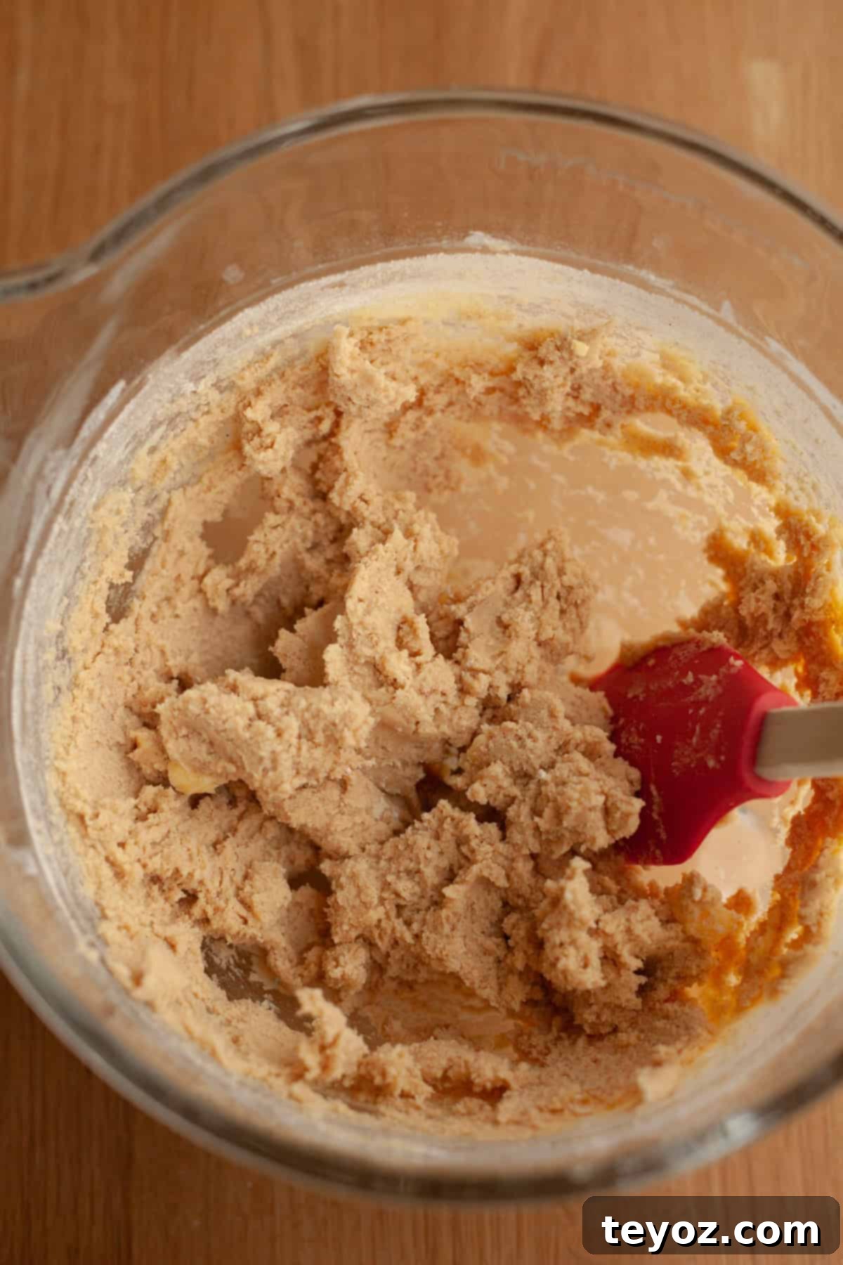A captivating close-up showcasing a large glass mixing bowl filled with perfectly combined cinnamon shortbread cookie dough, promising a batch of delectable treats.